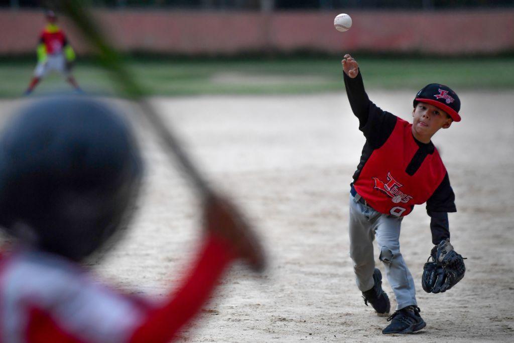 Un niño de unos 5 años lanza la pelota a otro que se dispone a batear.