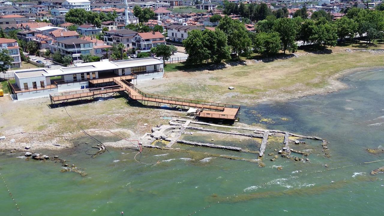 Fotografía aérea del yacimiento de Iznik. Se pueden apreciar mampostería parcialmente sumergida, delineando los antiguos muros de una iglesia, y un mirador se extiende hacia las aguas desde un edificio cercano.