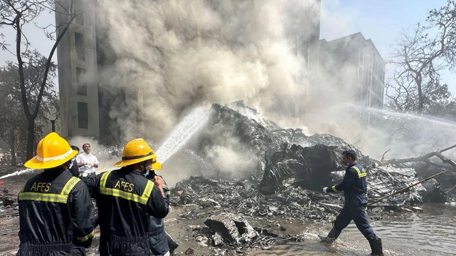 Bomberos con mangueras intentan controlar el incendio que dejó el avión al impactar pocos minutos después del despegue.