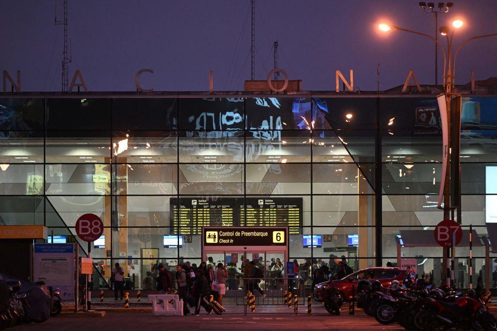 Personas caminan frente a la entrada del viejo aeropuerto Jorge Chávez de Lima en una imagen nocturna. 