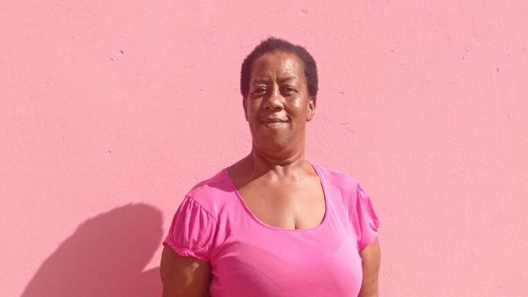 Miranda Beazer, usando uma blusa rosa diante de um fundo cor-de-rosa