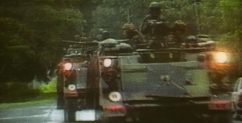 Militares sobre tanques na rua, com um fundo cheio de &aacute;rvores