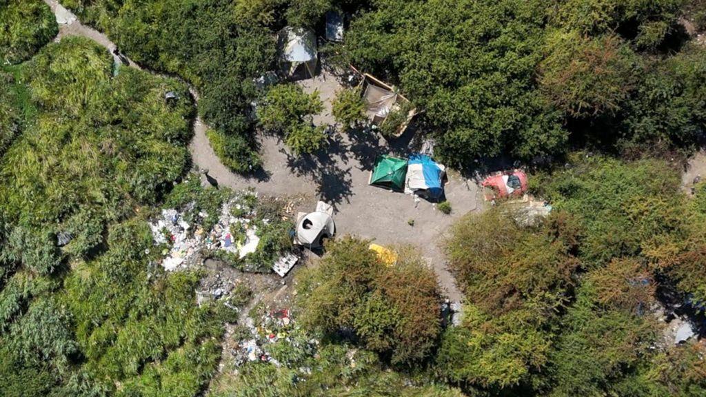 صورة جوية التقطتها طائرة بدون طيار لمخيم المهاجرين قرب دونكيرك. هناك مساحات خضراء واسعة، ثم فسحة في الوسط حيث يمكن رؤية الخيام.