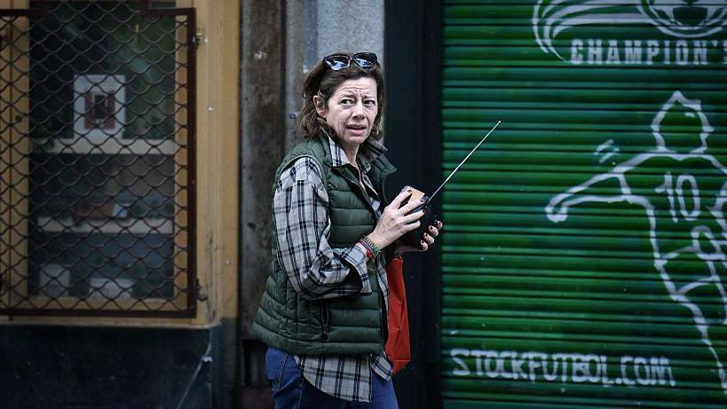 Una mujer en la calle sintoniza una radio.