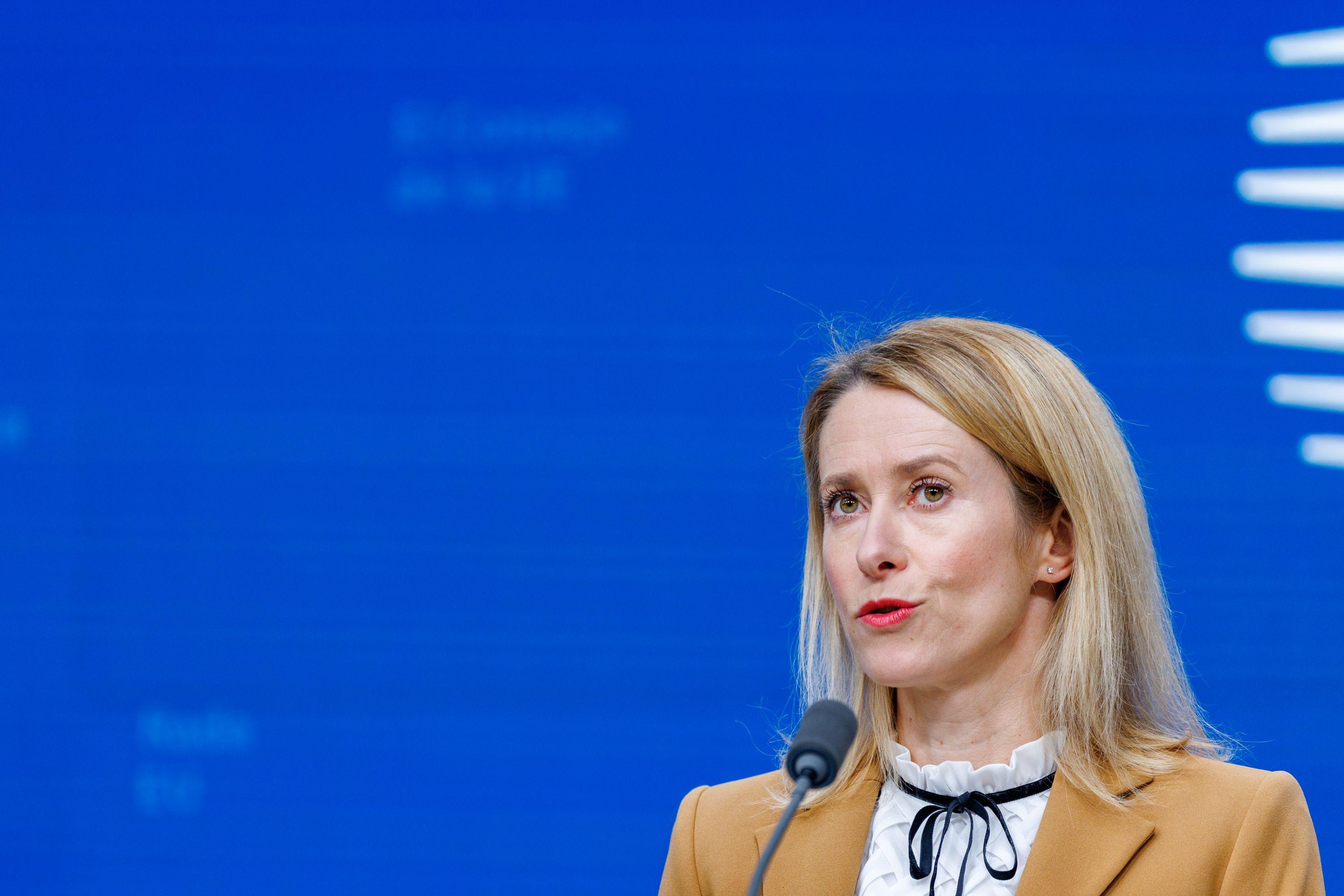 Zamrznuta ruska imovina: Šta hoće EU i zašto se Belgija protivi 10 Obučena u bež jaknu i beli top sa crnom čipkom, šefica spoljne politike EU Kaja Kalas govori u mikrofon na svetlo plavoj pozadini sa belim grafičkim elementima