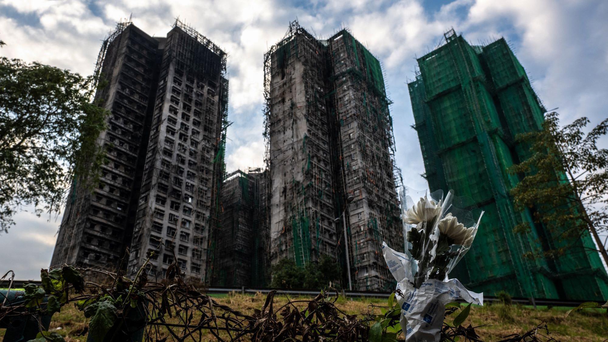 Flowers are seen in front of the Wang Fuk Court apartment blocks in the aftermath of the deadly November 26 fire in Hong Kong's Tai Po district on December 3, 2025. 