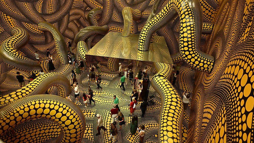 Visitantes recorren la instalación "Sala de Espejos Infinitos: La Esperanza de los Lunares Enterrados en el Infinito Cubrirán Eternamente el Universo" de la exposición de Yayoi Kusama en el Museo Ludwig de Colonia, Alemania.