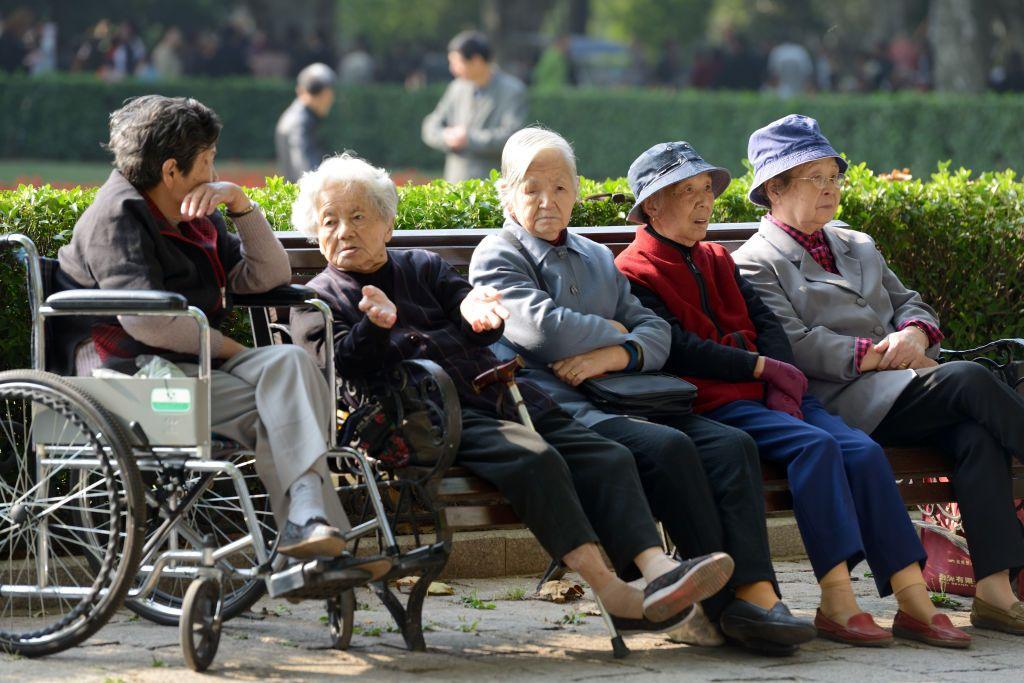 Um grupo de mulheres idosas sentadas em um banco no Parque Fuxing, em Xangai