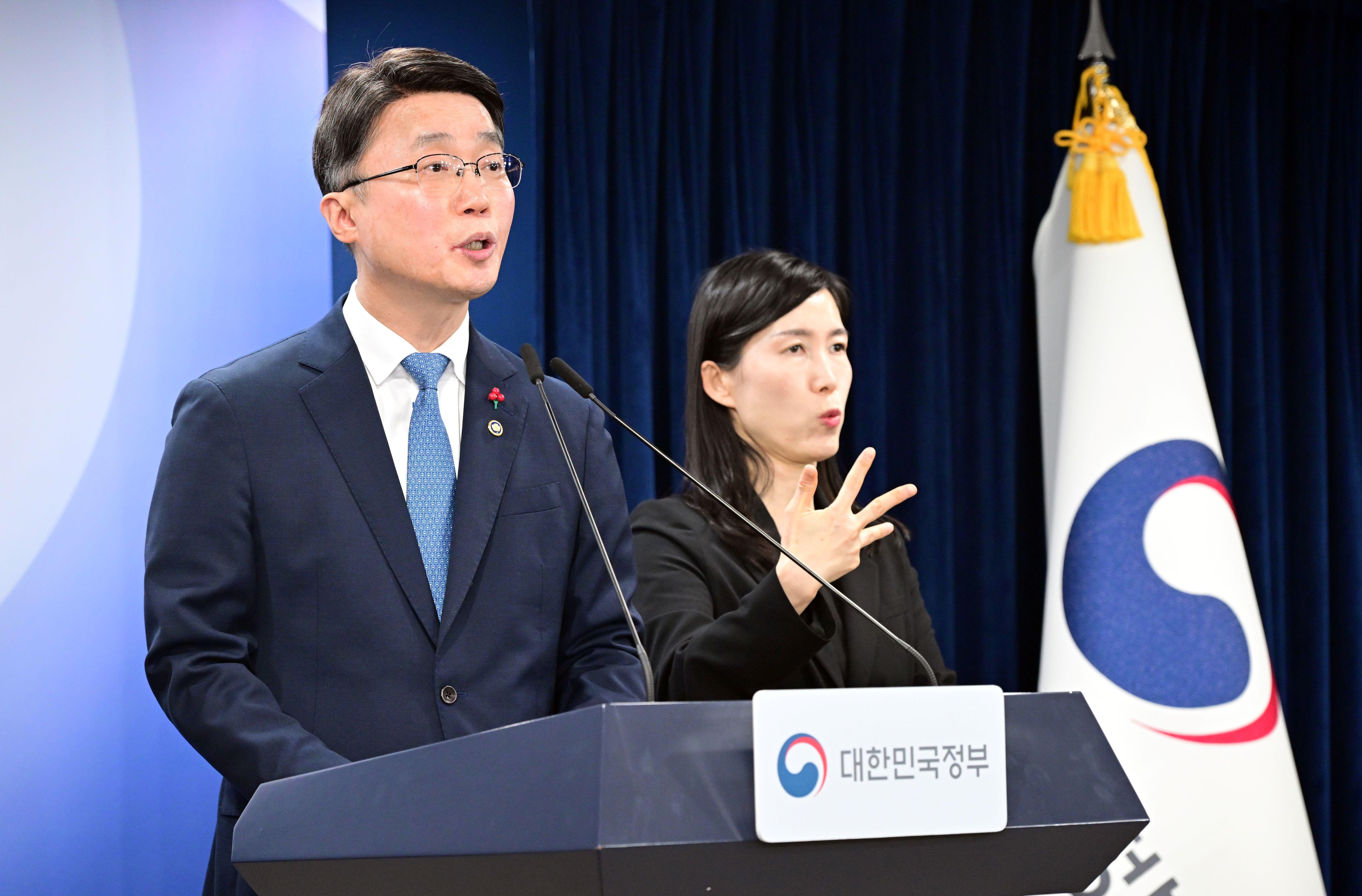 대한민국정부 로고가 그려져 있는 국기 옆에서 류제명 과학기술정보통신부 2차관이 마이크 앞에 서서 브리핑하고 있다. 그 옆에는 여성 수어 통역사가 그 말을 수어로 전하고 있다.  