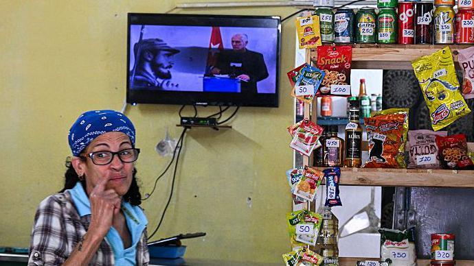 En una tienda en La Habana se ve un televisor encendido con la imagen de Díaz-Canel. Hay una mujer con lentes que parece estar siguiendo lo que dice.