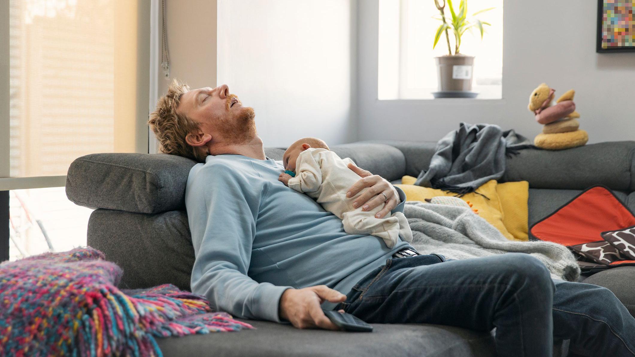 رجل منهك وعلى صدره طفل نائم