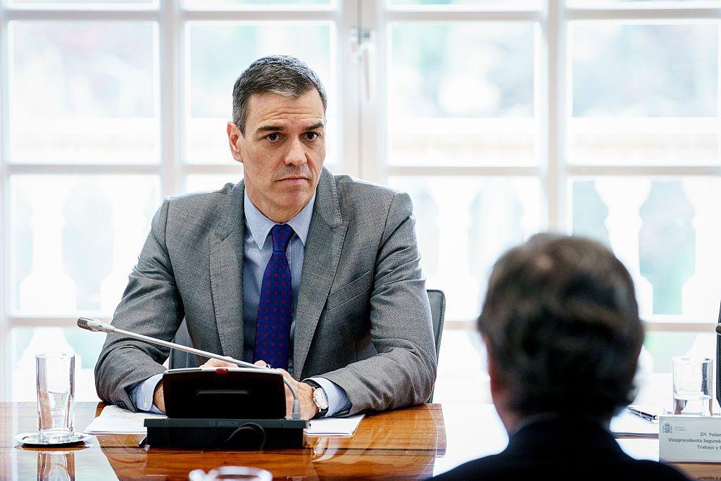 Pedro Sánchez sentado en una mesa con un micrófono. 