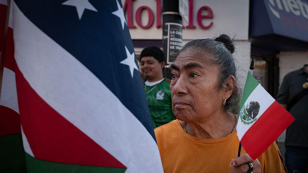 Una mujer en "La Villita" con las banderas de EE.UU. y México.