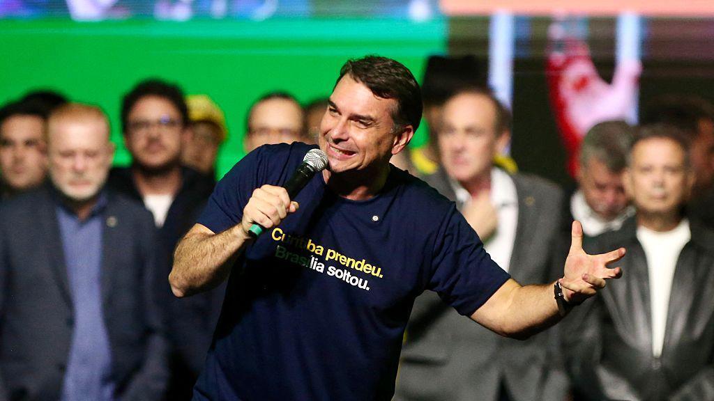 Fl&aacute;vio Bolsonaro durante evento falando ao microfone.