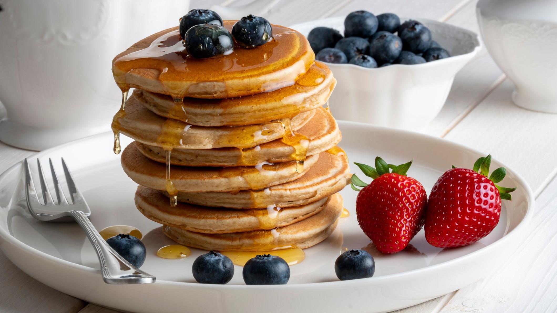 Prato de panquecas cobertas com frutas e calda  