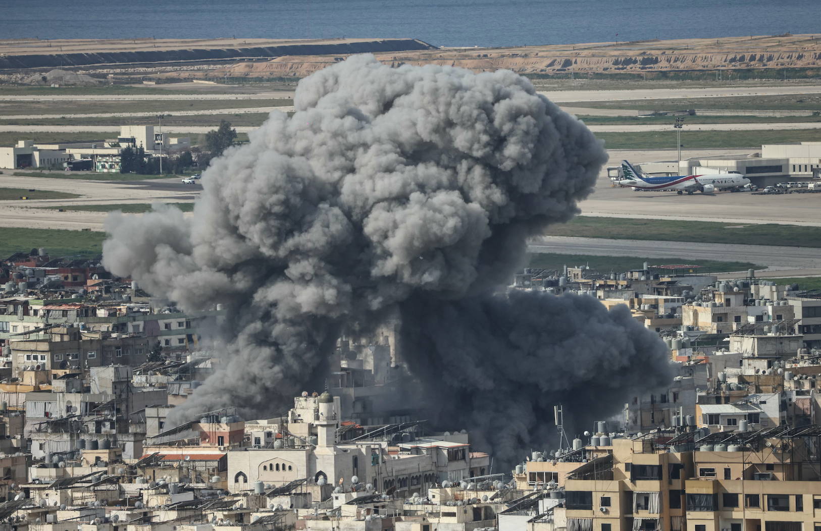 يتصاعد الدخان من موقع غارة جوية إسرائيلية استهدفت حي الليلكي في الضاحية الجنوبية لبيروت، مع ظهور مطار المدينة الدولي في الخلفية، في 4 مارس/آذار 2026.