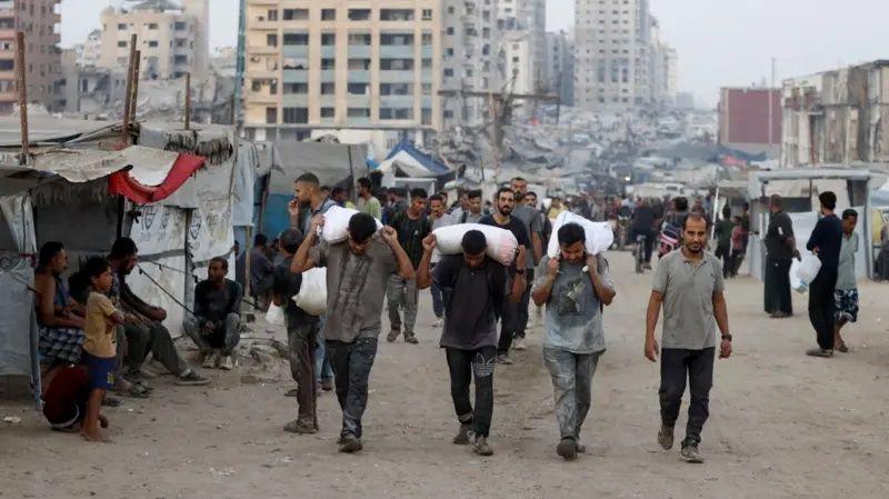 Homens carregando vários sacos nas costas 