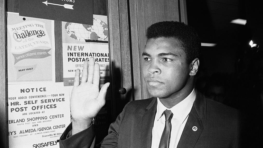 الملاكم الأمريكي ملوحا بيده ويرتدي بزة وربطة عنق