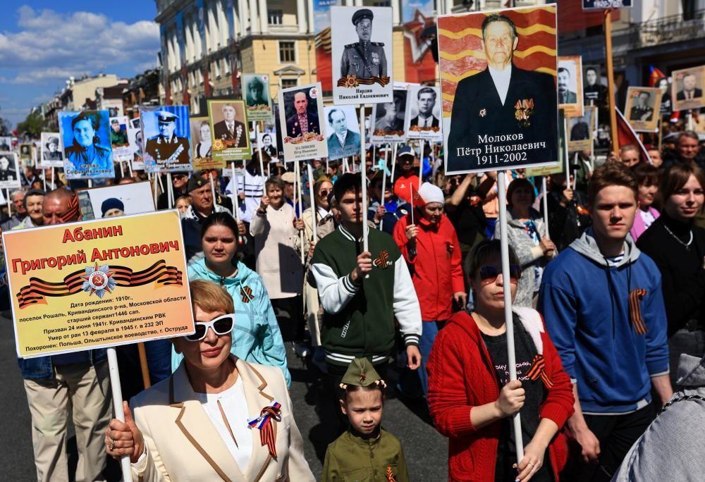 Una multitud de personas desfila por una calle portando pancartas con imágenes de soldados y veteranos durante una marcha del "Regimiento Inmortal" en Vladivostok.