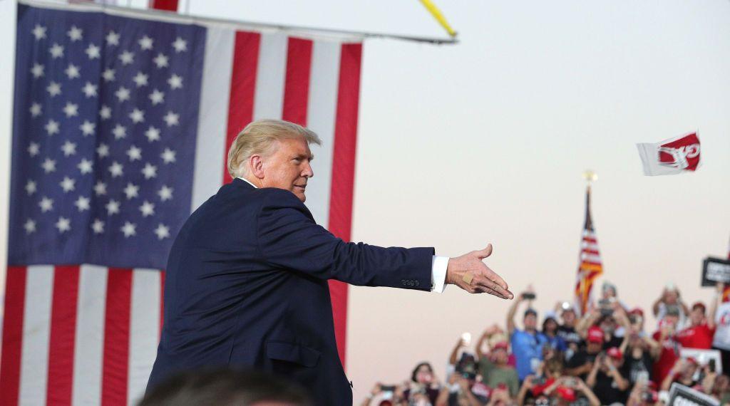 El presidente Donald Trump lanza mascarillas MAGA a la multitud de simpatizantes a su llegada a un mitin de campaña en el Aeropuerto Internacional Orlando Sanford, en Sanford, Florida, el lunes 12 de octubre de 2020.