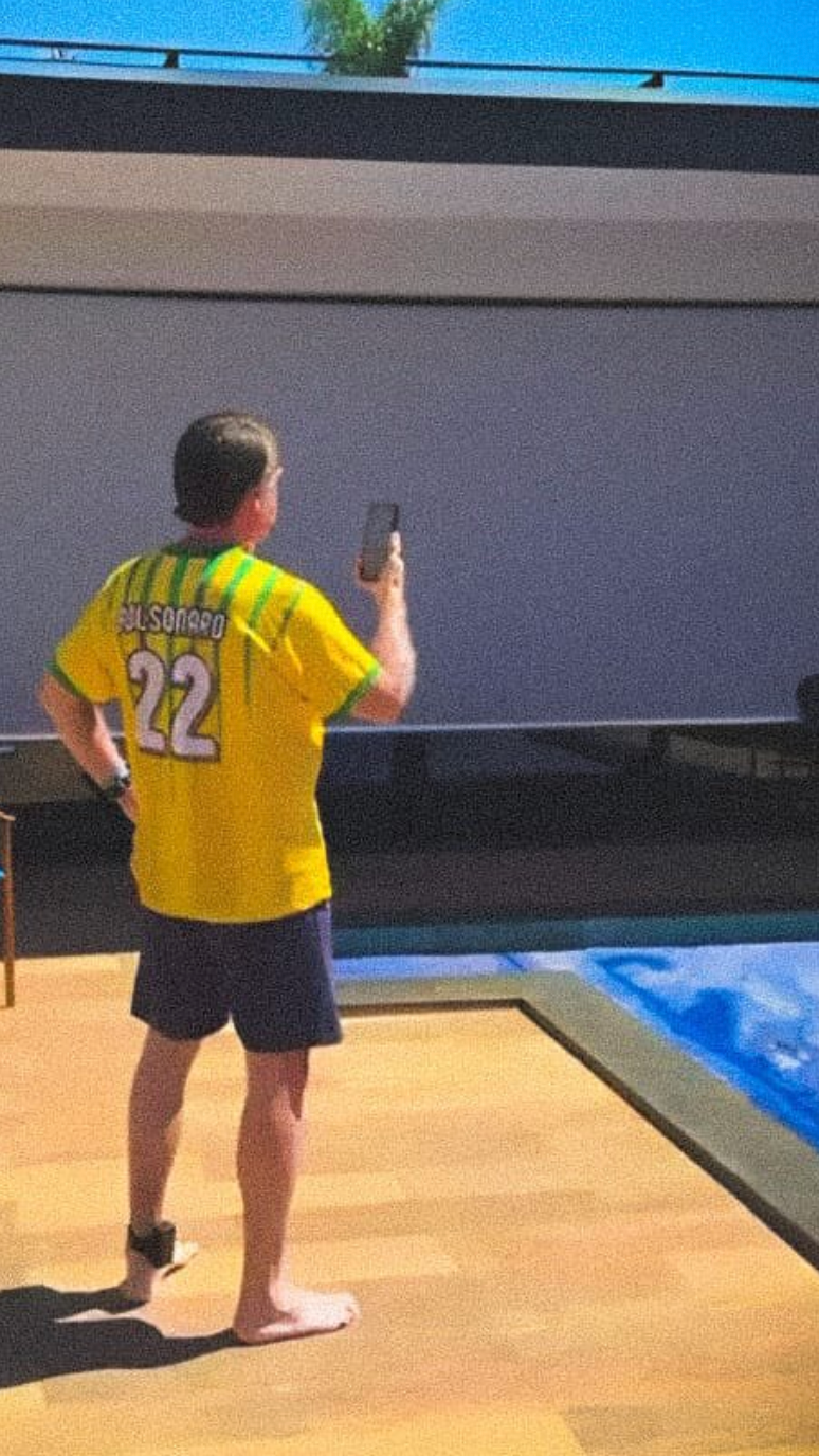 Bolsonaro usa o telefone à beira da piscina da casa onde ele irá cumprir prisão domiciliar