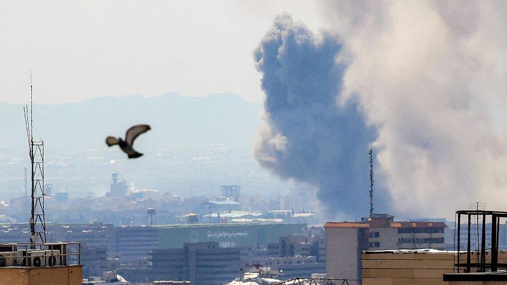 Uma coluna de fuma&ccedil;a se eleva sobre Teer&atilde; ap&oacute;s um ataque com m&iacute;sseis &agrave; cidade no in&iacute;cio de abril de 2026. Um pombo &eacute; visto subindo ao c&eacute;u ap&oacute;s a perturba&ccedil;&atilde;o.