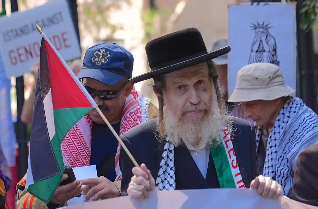 أحد اليهود "المناهضين للصهيونية" يرفع العلم الفلسطيني ويرتدي الكوفية الفلسطينية ضمن احتجاج مؤيد للفلسطينيين أمام مكتبة نيويورك العامة، وساروا إلى حديقة داغ همرشولد، عابرين الطريق إلى الأمم المتحدة، قبل أيام من انعقاد الدورة الثمانين للجمعية العامة للأمم المتحدة. الصورة التُقطت في يوم الخميس سبتمبر/أيلول ، في مدينة نيويورك، الولايات المتحدة الأمريكية.