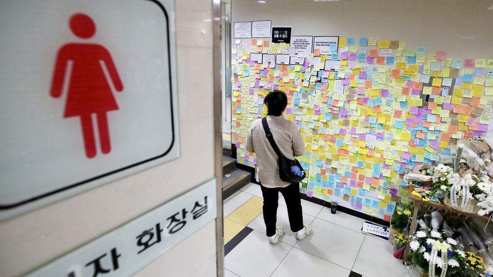 Una persona lee los mensajes en la pared de un baño de mujeres en Corea del Sur. 