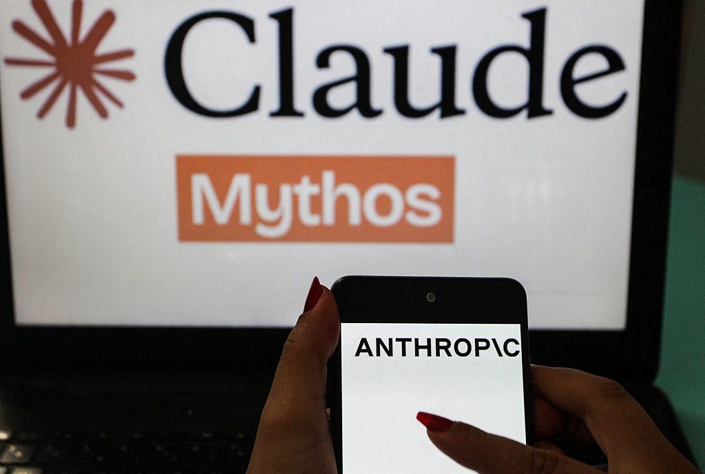 En primer plano se muestra un teléfono inteligente con el logotipo de Anthropic, con un fondo desenfocado de temática Claude Mythos.
