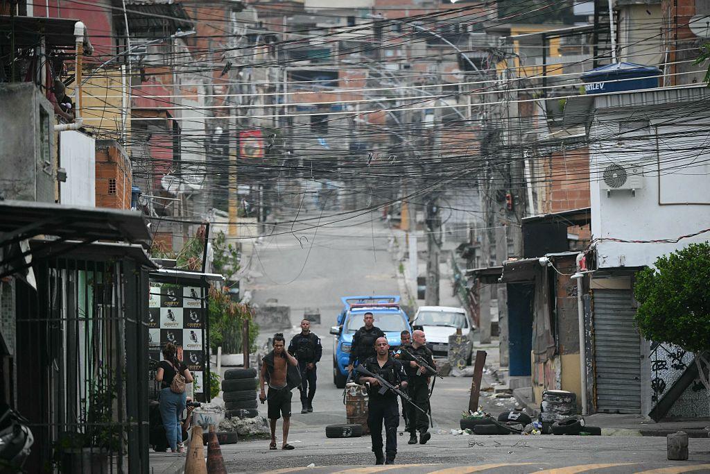 Policiais fortemente armados e pessoas na rua durante operação na favela