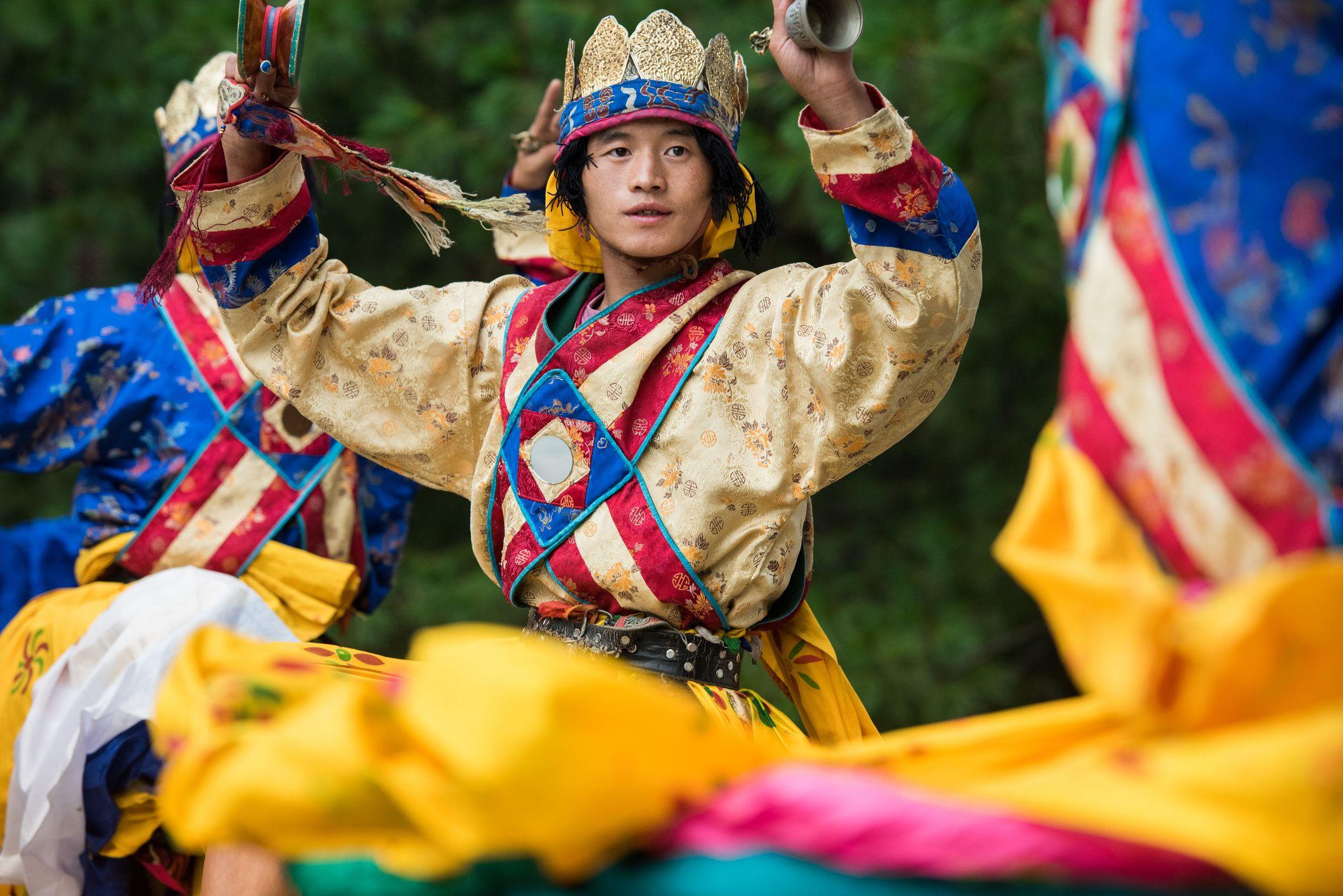 Un joven realiza un baile tradicional de Bután vestido con coloridas ropas.