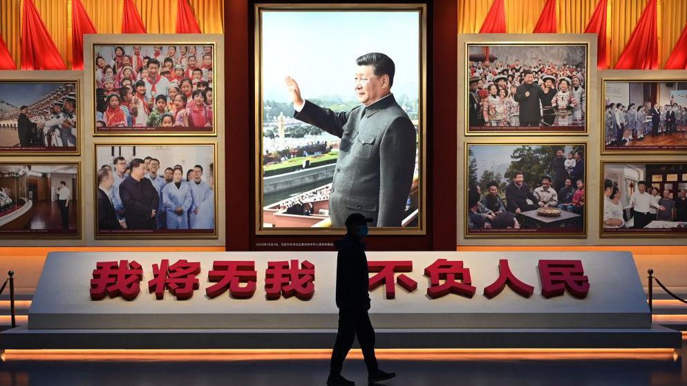 一位男子走過掛滿習近平肖像的展覽臺前