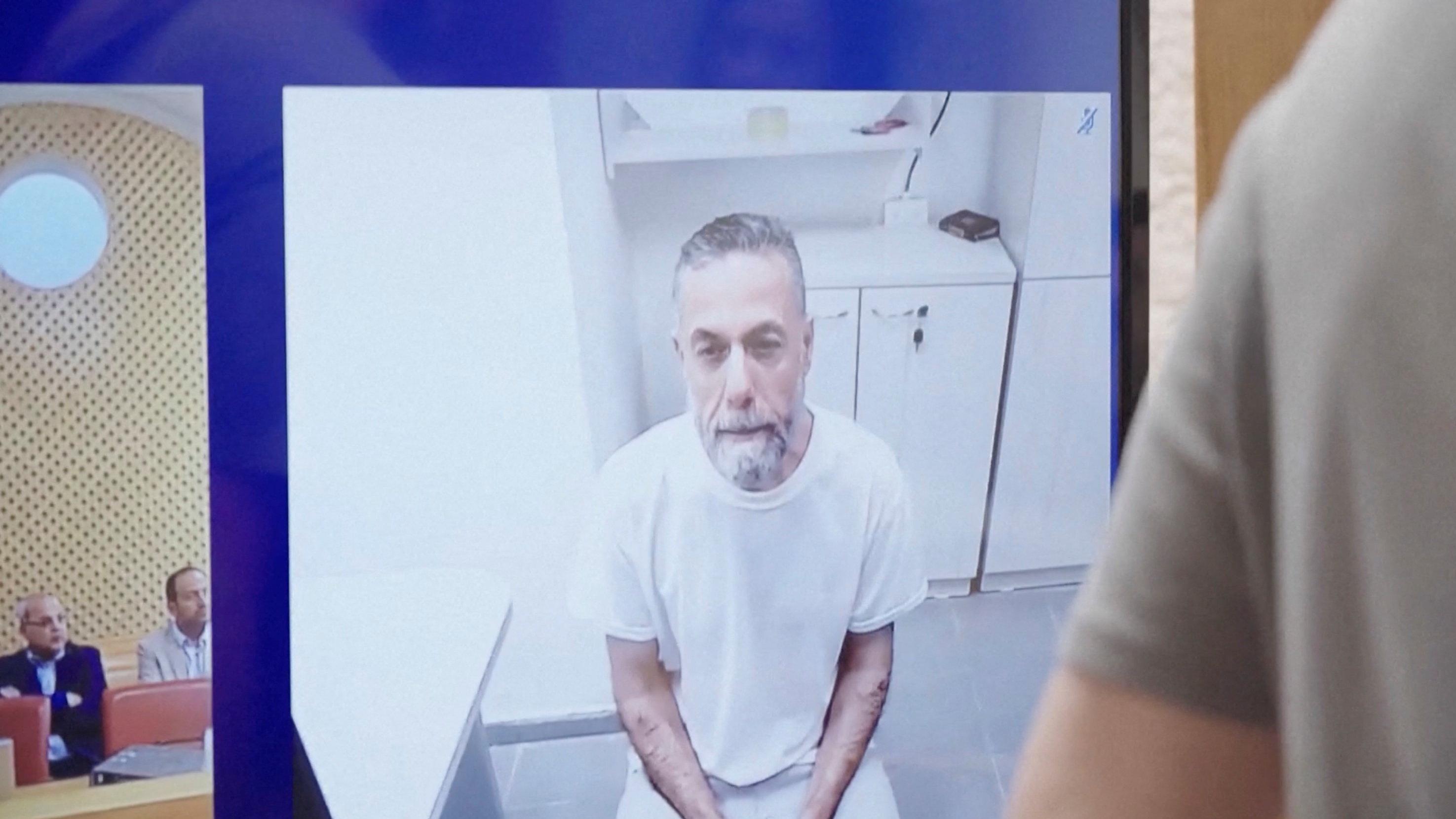 El médico palestino detenido, Hassam Abu Safiya, aparece en una pantalla vestido con una camisa blanca en prisión durante una audiencia ante la Corte Suprema israelí el 10 de junio de 2026.