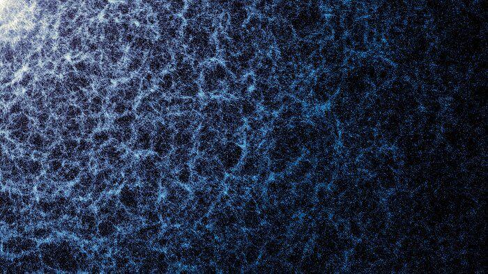 Una imagen de fondo negro con una textura de filamentos y puntos azules y blancos, con unas zonas más densas y de color más intenso que otras.
