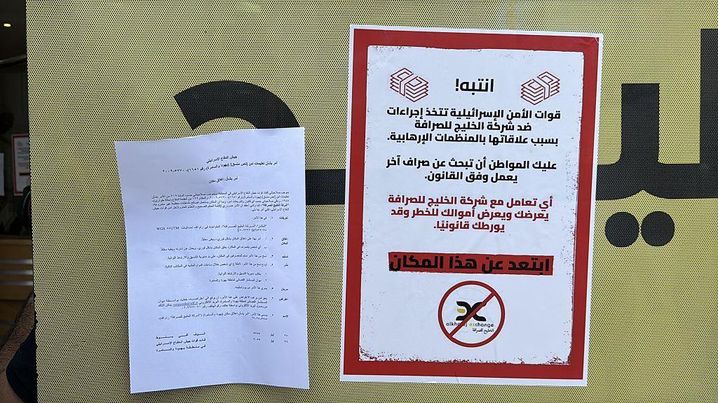 عُلّقت ملصقات تحذيرية على نوافذ المكاتب، تحذر المواطنين من إجراء أي معاملات مالية، بعد أن نفذت القوات الإسرائيلية مداهمات متزامنة لفروع شركة "الخليج" للصرافة في رام الله، الضفة الغربية، في ٢٧ مايو/أيار ٢٠٢٥.