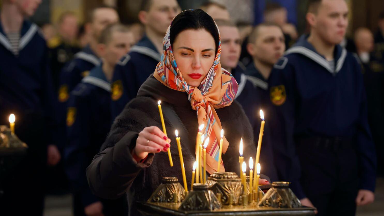 Devojka sa maramom na glavi pali sveću