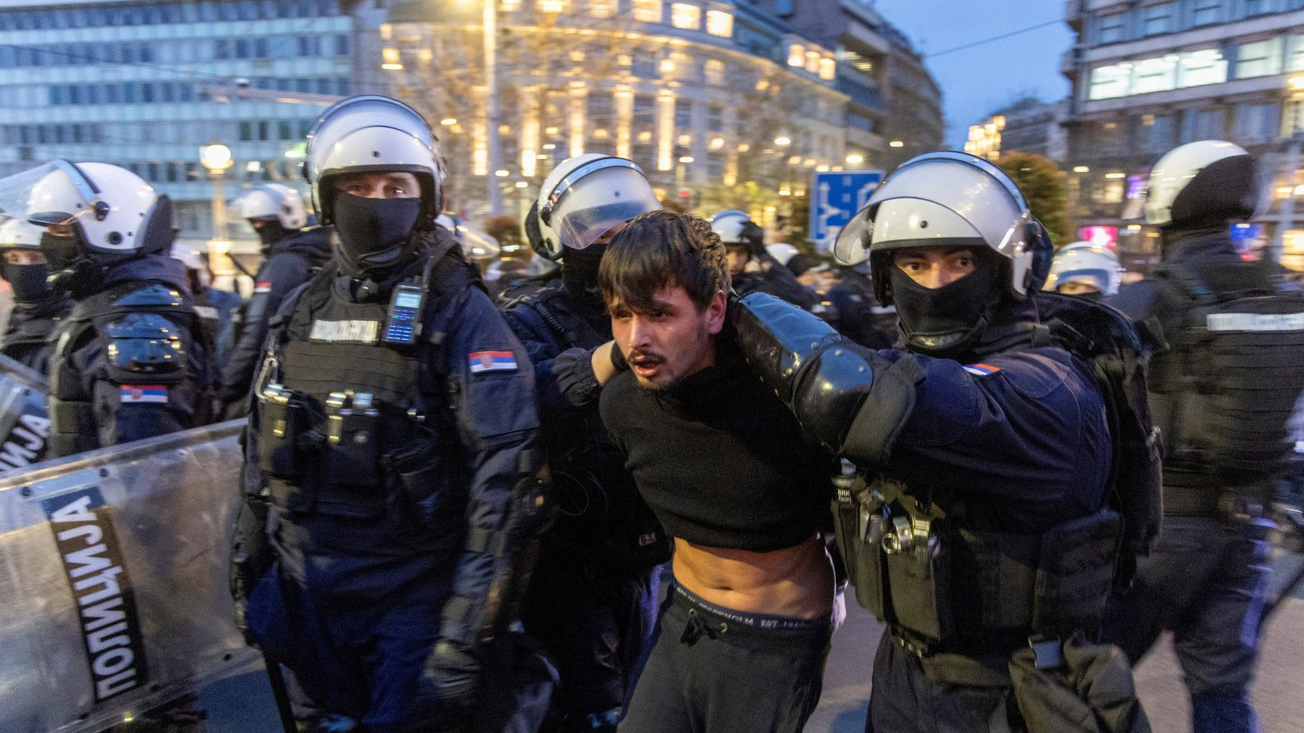 Policija hapsi mlađeg muškarca, drži mu ruke na leđima 