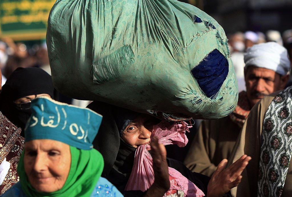 سيدة ريفية مصرية تحمل أمتعتها فوق رأسها، وتسير في موكب الاحتفال بالمولد النبوي في القاهرة، في 26 فبراير/شباط 2010.