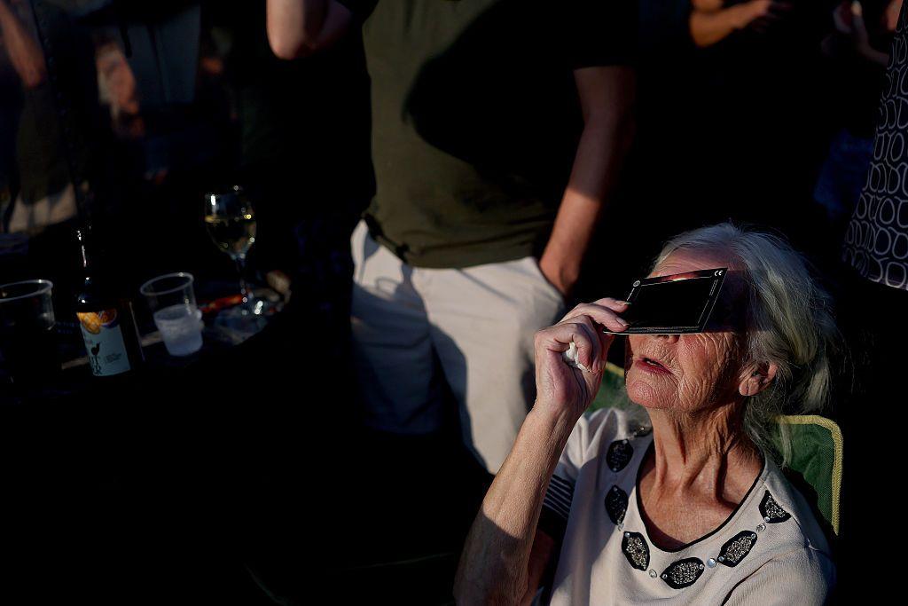 Una mujer mayor con una película protectora mira el eclipse en Reino Unido. 