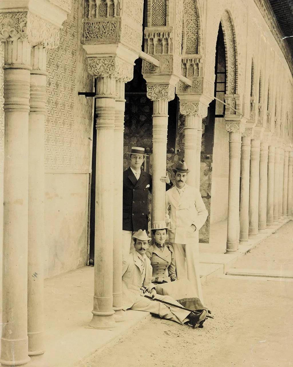 Foto de George W Vanderbilt con amigos en Granada, España. En la imagen se ve a Vanderbilt, dos amigos y una amiga, con atuendos de la época y sombreros, en una antigua construcción con arcos en Granada.