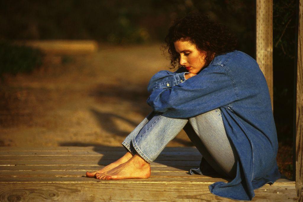 سيدة تجلس على الأرض وعليها علامات اكتئاب