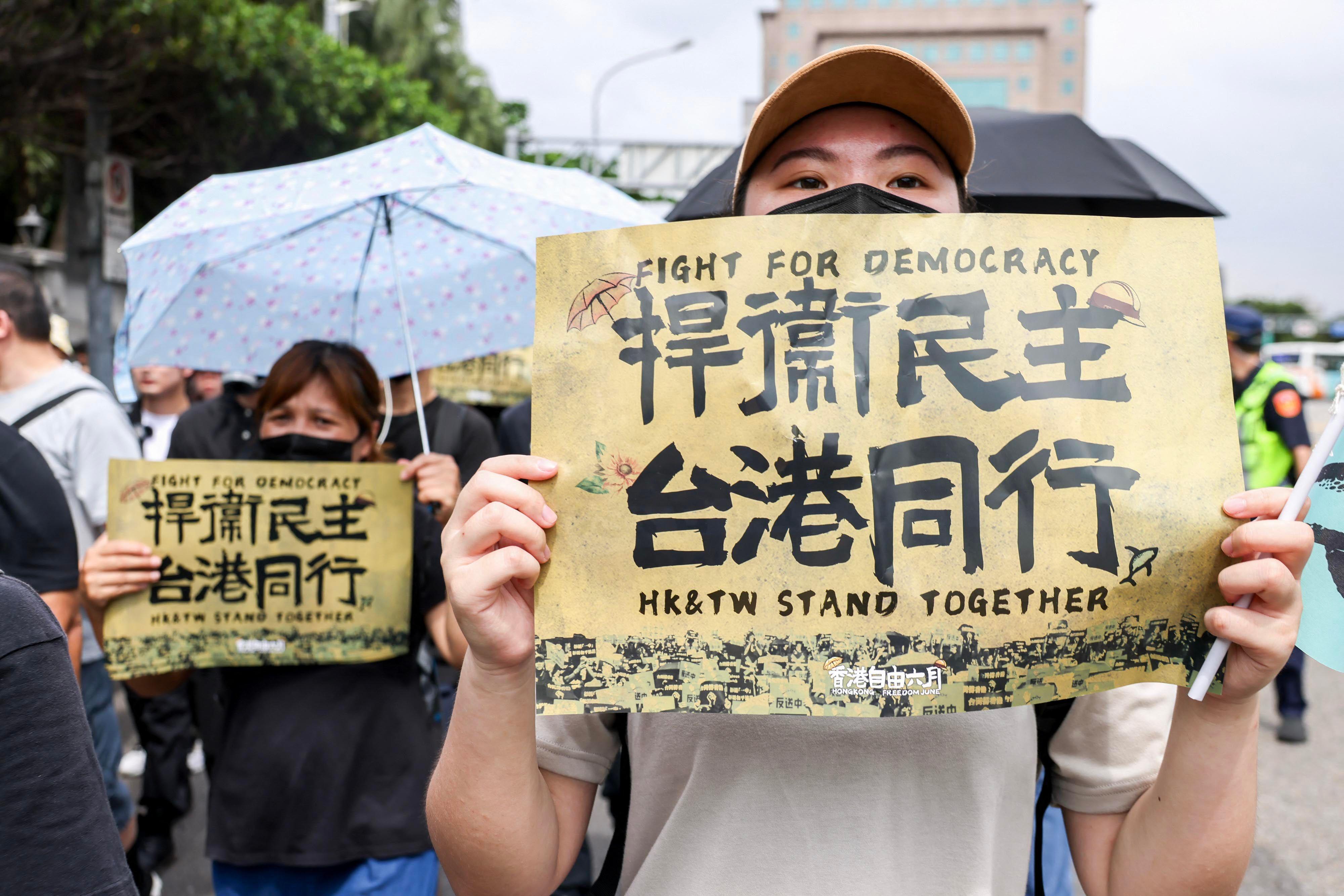 一些人士在街頭遊行，有人舉起寫上「捍衛民主，台港同行」的海報。