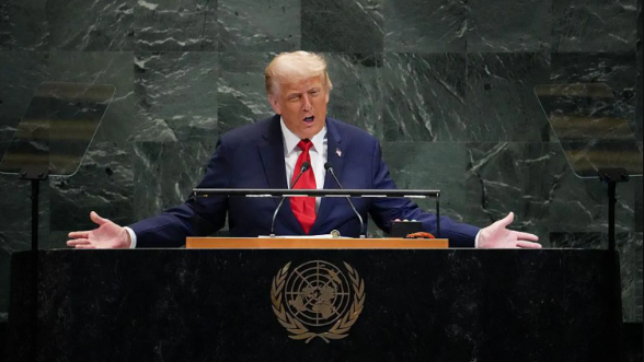 الرئيس الأمريكي دونالد ترامب متحدثاً داخل مبنى الأمم المتحدة مرتدياً بدلة رسمية.
