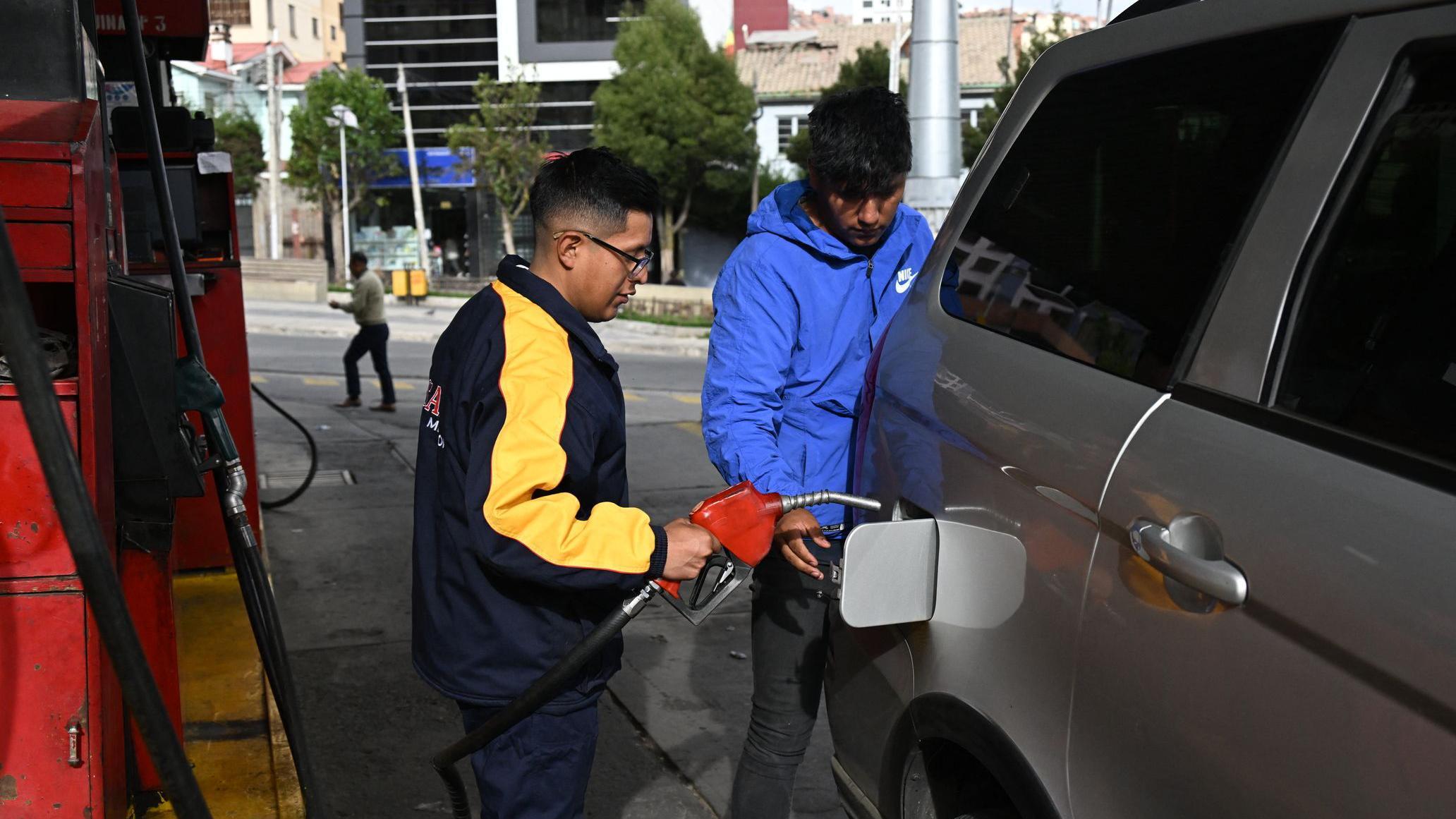 Un hombre carga combustible a un auto en una gasolinera en Bolivia. 