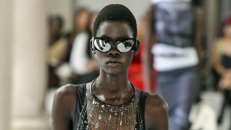 A modelo sul-sudanesa Akur Goi desfilando, de óculos espelhados