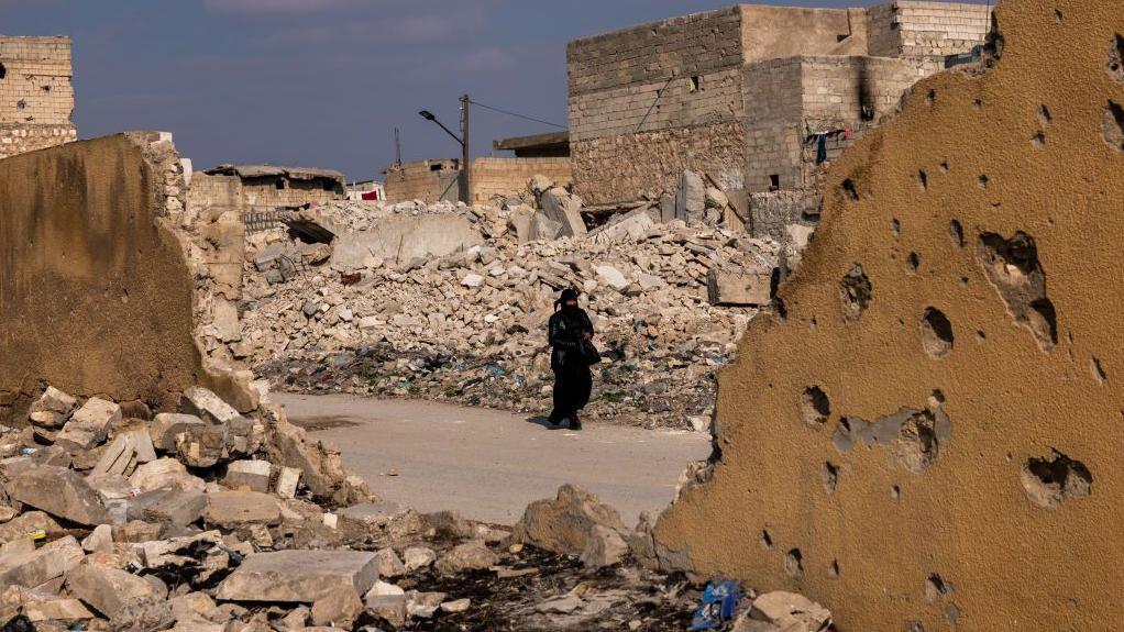 سيدة تمشي وسط الدمار في حلب كانون الثاني - يناير 2025