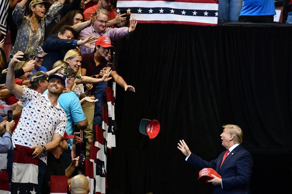 O presidente dos EUA, Donald Trump, joga bon&eacute;s do MAGA para apoiadores