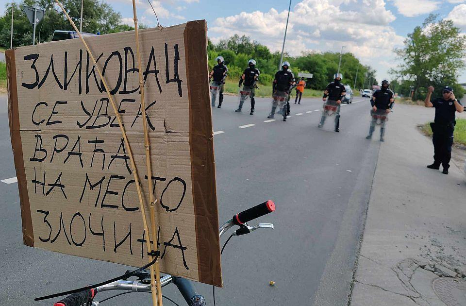 policija u Novom Sadu. Ispred njih bicikla sa transparentom "Zločinac se uvek vraća na mesto zločina"