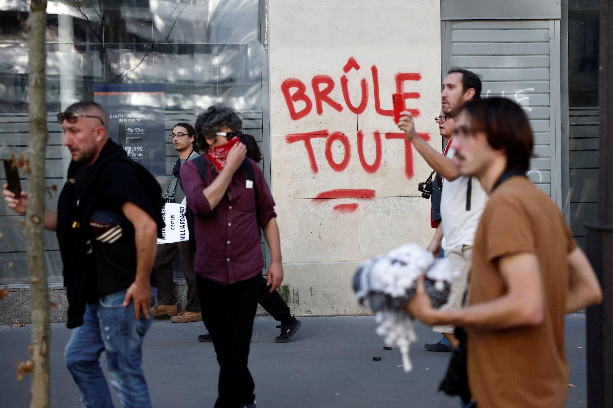 Manifestantes passam diante do slogan 