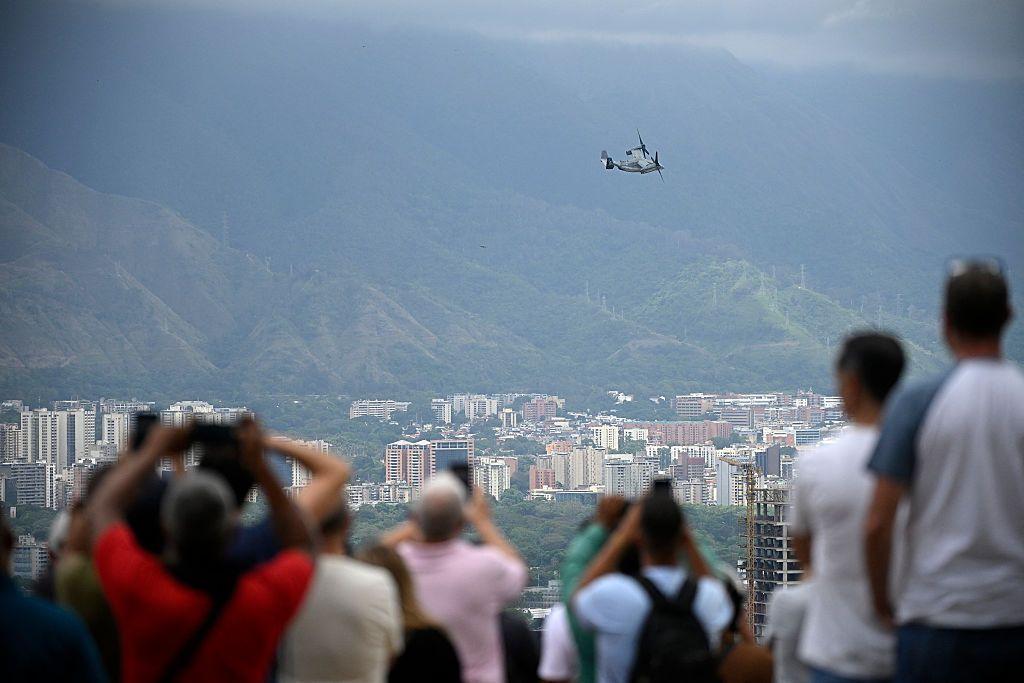 Varias personas toman fotos y videos de una aeronave militar de EE.UU. sobrevolando Caracas.